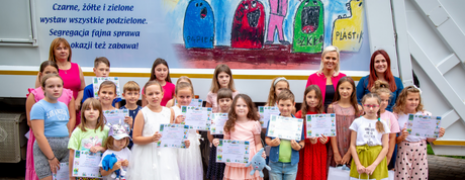 Zdjęcie grupowe, organizatorzy konkursu, dzieci biorące udział w konkursie a w tle kolorowa śmieciarka