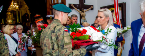 Kobieta przekazuje kwiaty żołnierzowi
