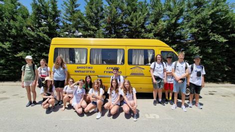 Grupa uczniów pozuje do zdjęcia przed zółtym busem
