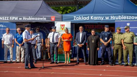 Burmistrz Miasta Marta Majewska przemawia przez mikrofon, za nią stoją mężczyźni w mundurach