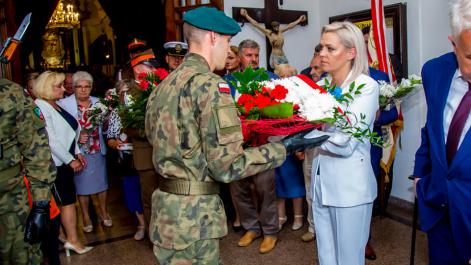Kobieta przekazuje wiązankę kwiatów żołnierzowi