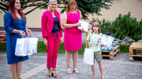 Dziewczynka pozuje do zdjęcia z burmistrzem i prezesem PGKiM oraz otrzymanymi nagrodami