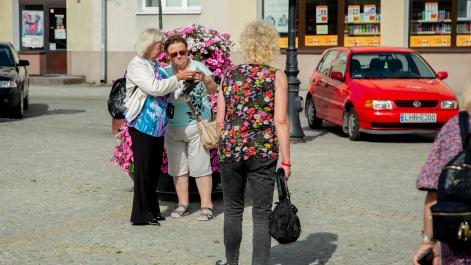 Kobiety pozują do zdjęcia przy kompozycji kwiatowej na deptaku