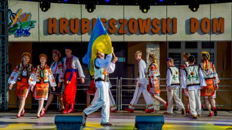 Zespół z Ukrainy tańczy, trzymają Ukraińską flagę