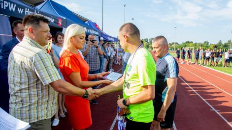 Marta Majewska wręcza pamiątkową tabliczkę, obok mężczyzna gratuluje piłkarzowi 