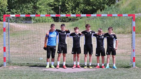 Młodzi piłkarze pozują do zdjęcia, obęci ramionami chłopcy stoją w bramce